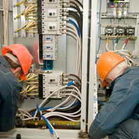Two electricians working on a industrial panel mounting and assembling new wiring
